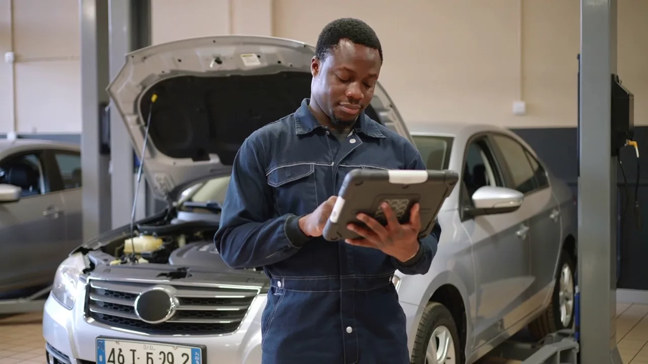 Illustrative mechanic reviewing a vehicle diagnosis on a tablet